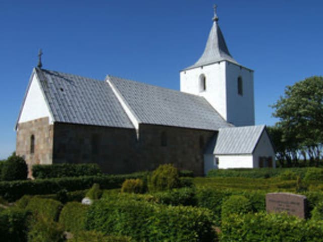 Gammel sogn kirke på en solskinsdag med blå himmel og høj sol